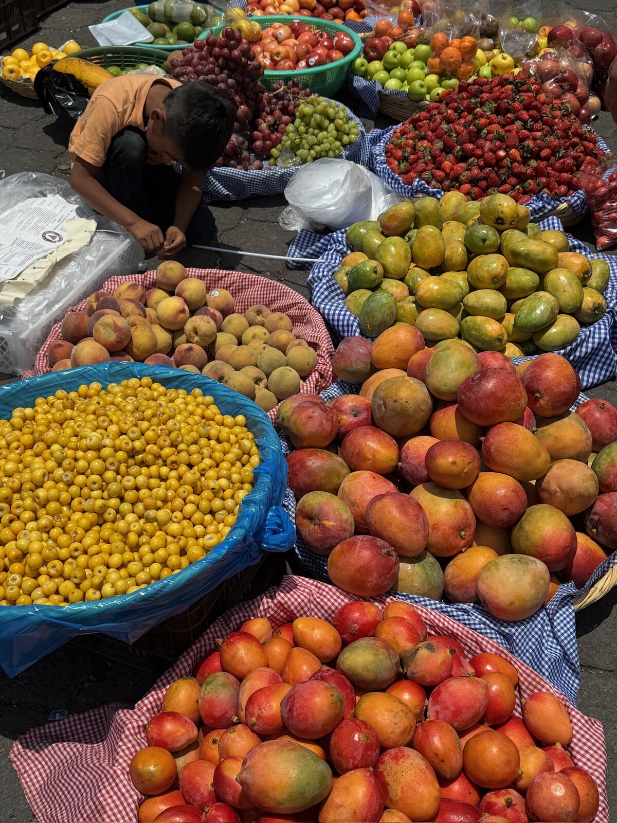 A vendor's baskets of mangoes, peaches and nances at a market in Guatemala