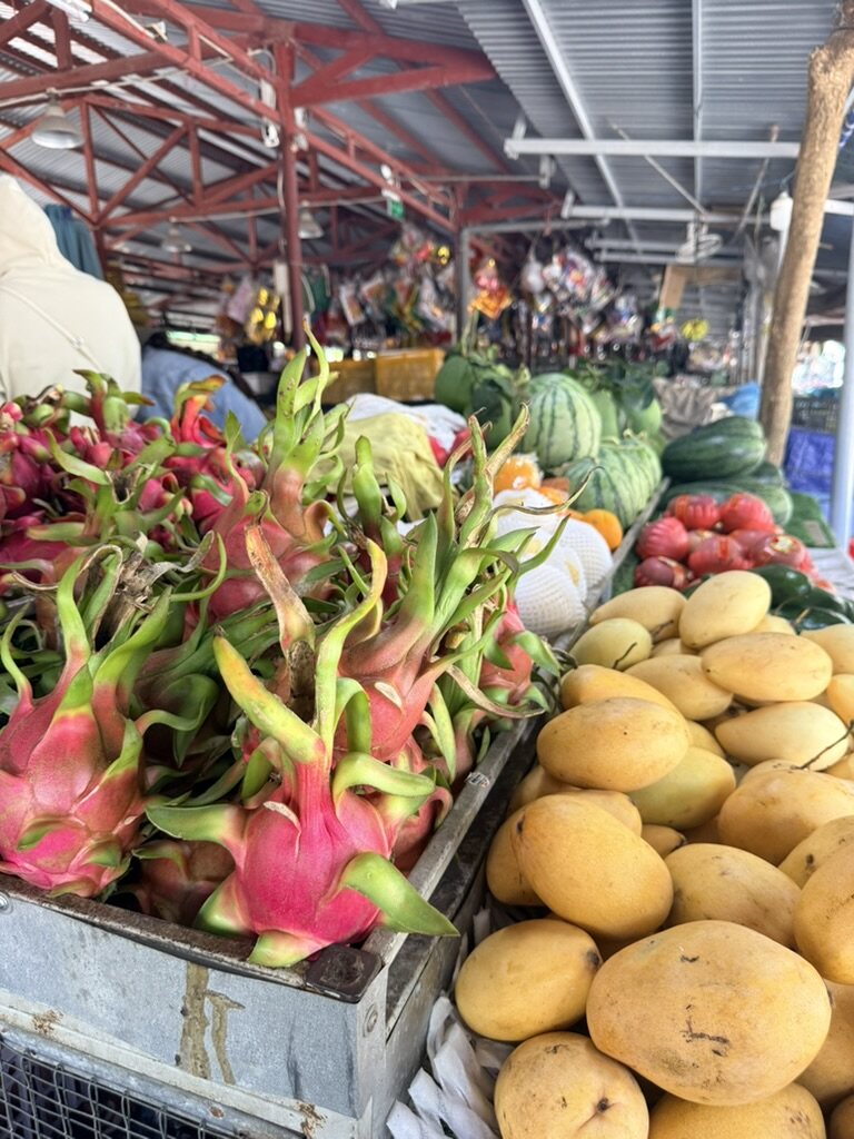 Dragon fruit and mangoes piled high at a market stall in Hoi An, Vietnam